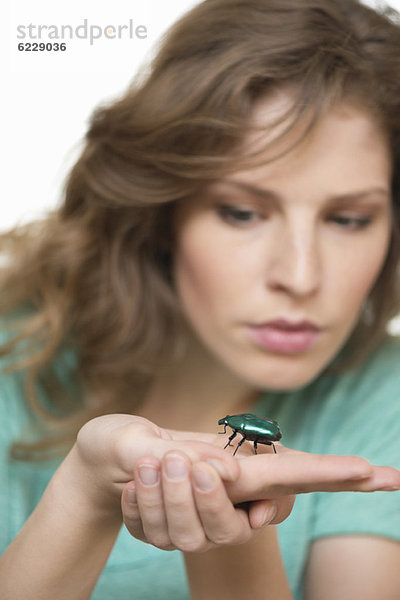 Frau schaut auf einen Käfer an der Hand