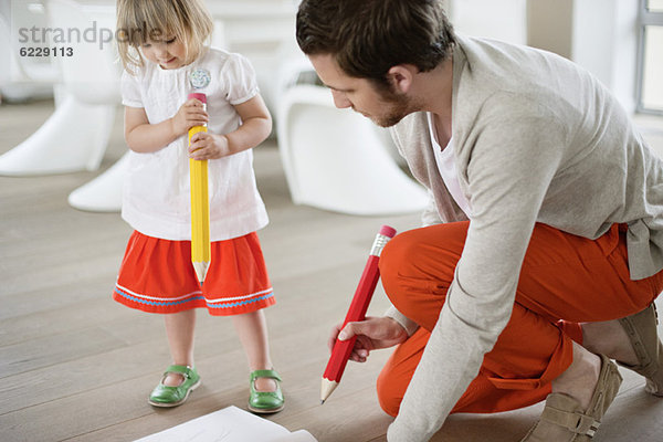Mann und seine Tochter zeichnen mit großen Bleistiften