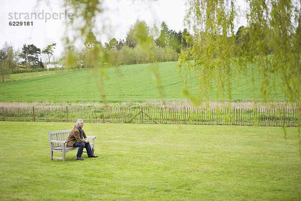 Mann auf einer Bank auf einem Feld sitzend