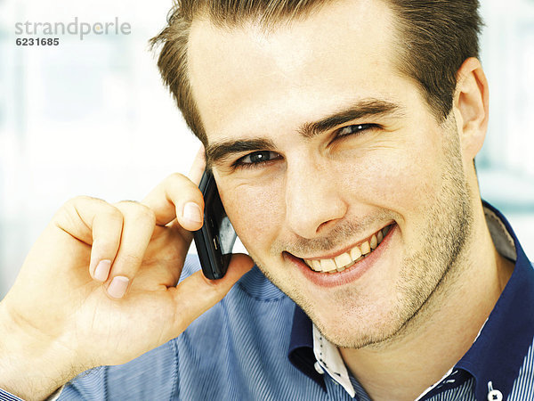Lächelnder junger Mann telefoniert mit Handy