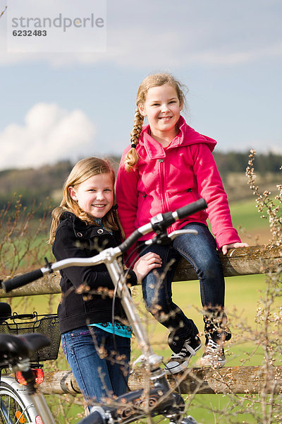 Zwei Mädchen mit Fahrrädern in ländlicher Umgebung