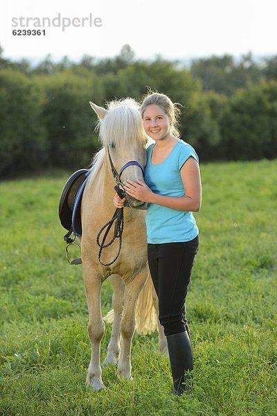 Lächelndes Mädchen mit Pferd auf einer Wiese