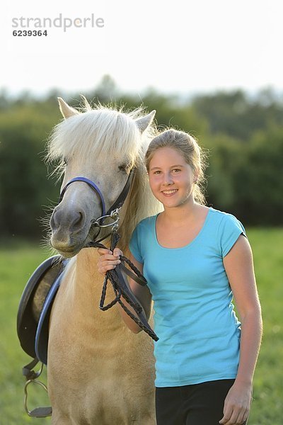 Lächelndes Mädchen mit Pferd auf einer Wiese