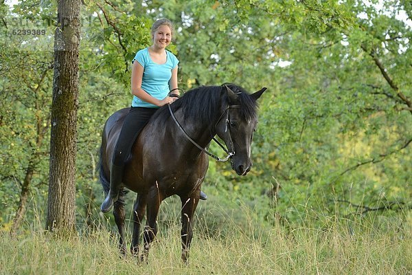 Lächelndes Mädchen reitet auf einem Pferd