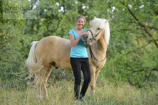 Lächelndes Mädchen mit Pferd auf einer Wiese