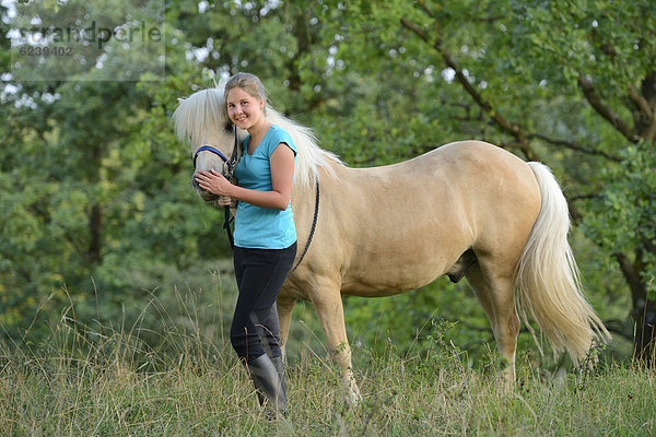 Lächelndes Mädchen mit Pferd auf einer Wiese