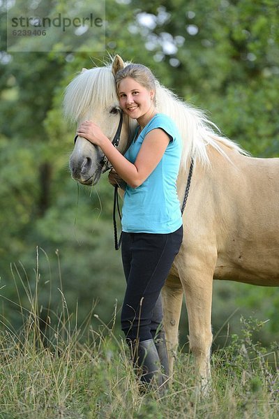 Lächelndes Mädchen mit Pferd auf einer Wiese