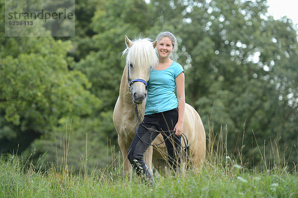 Lächelndes Mädchen mit Pferd auf einer Wiese