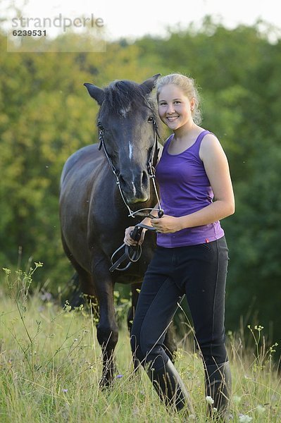 Lächelndes Mädchen mit Pferd auf einer Wiese