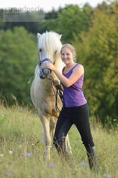 Lächelndes Mädchen mit Pferd auf einer Wiese