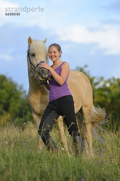 Lächelndes Mädchen mit Pferd auf einer Wiese