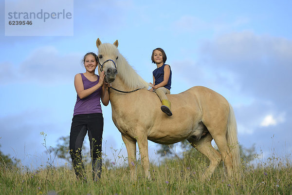 Zwei Mädchen mit Pferd auf einer Wiese