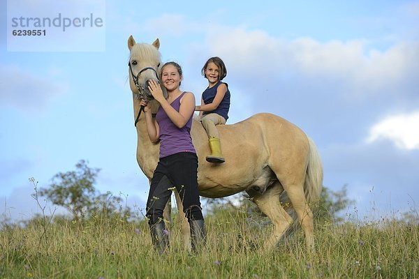 Zwei Mädchen mit Pferd auf einer Wiese