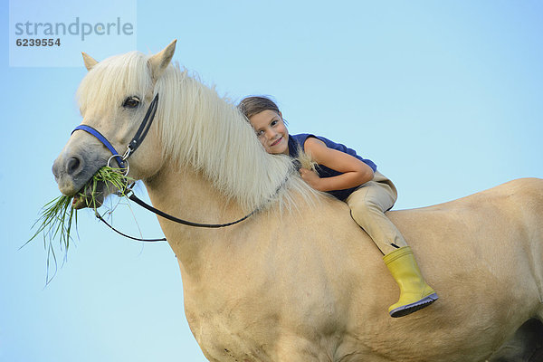 Mädchen sitzt auf einem Pferd