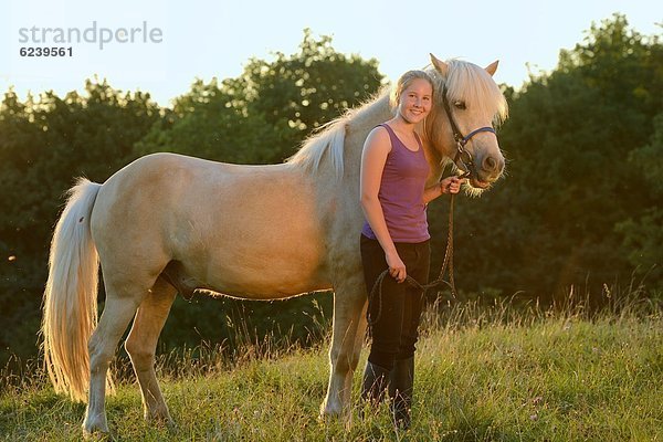 Lächelndes Mädchen mit Pferd auf einer Wiese