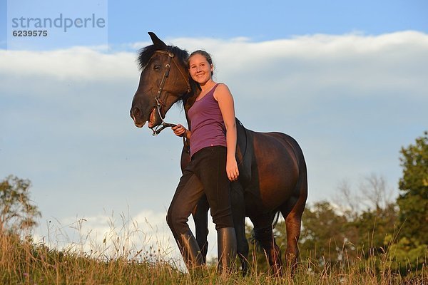 Lächelndes Mädchen mit Pferd auf einer Wiese