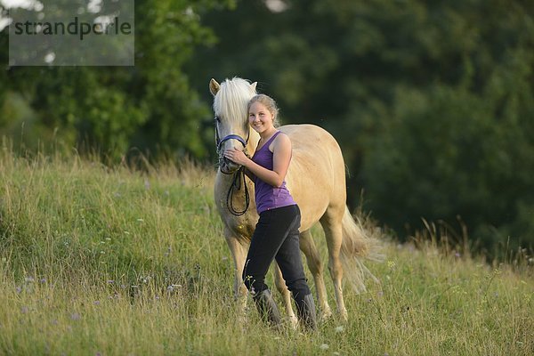 Lächelndes Mädchen mit Pferd auf einer Wiese