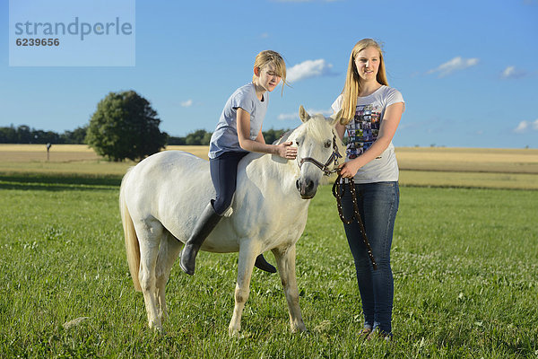 Zwei Mädchen mit Pferd auf einer Wiese