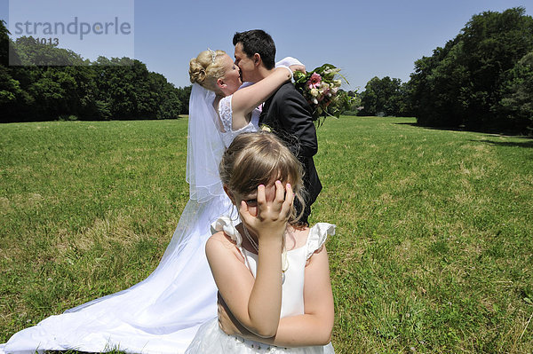 Hochzeit  junges Brautpaar küsst sich  kleines Mädchen hält sich verschämt die Augen zu
