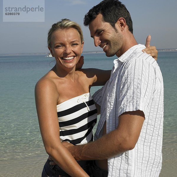 Paar umarmen am Strand  lächelnd