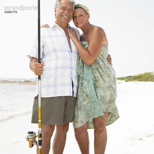 Senior couple on beach  man with fishing rod