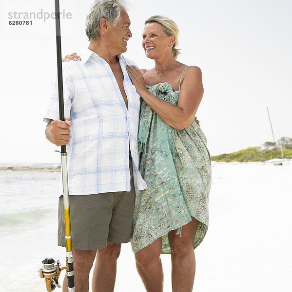 Senior couple on beach  man with fishing rod