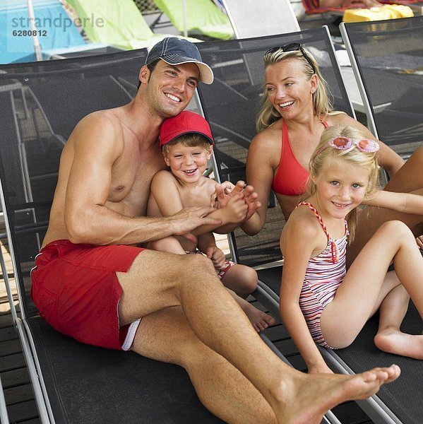 Family relaxing on sunloungers  children (6-8)