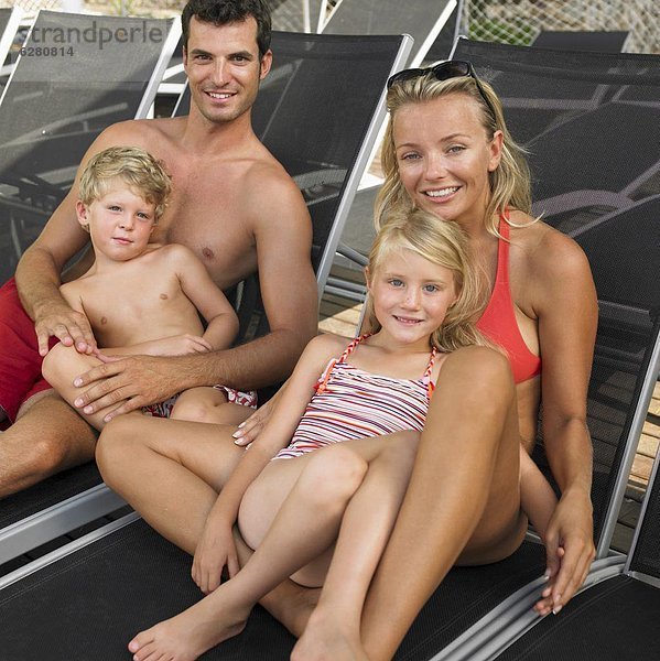 Family relaxing on sunloungers  children (6-8)