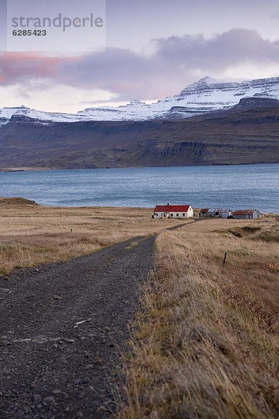 Berg Wohnhaus rot Dach bedecken Fjord Island Schnee