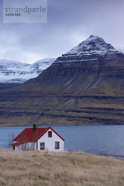 Berg Wohnhaus rot Dach bedecken Fjord Island Schnee