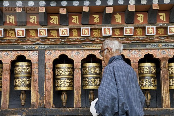 Alte bhutanesischen man drehen Gebetsmühlen in buddhistischen Tempel  Thimphu  Bhutan  Asien