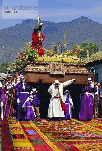 Farbaufnahme Farbe Mann tragen über groß großes großer große großen Teppichboden Teppich Teppiche Mittelamerika Christ Guatemala Sägemehl