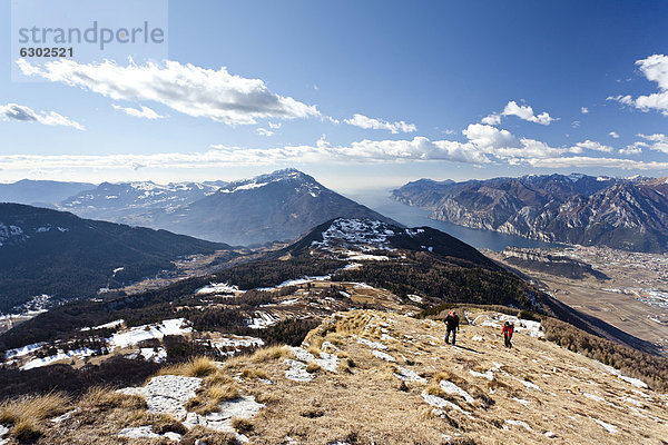 Wanderer beim Aufstieg zum Monte Stivo oberhalb von St. Barbara am Gardasee  hinten der Gardasee mit dem Dorf Riva  Trentino  Italien  Europa