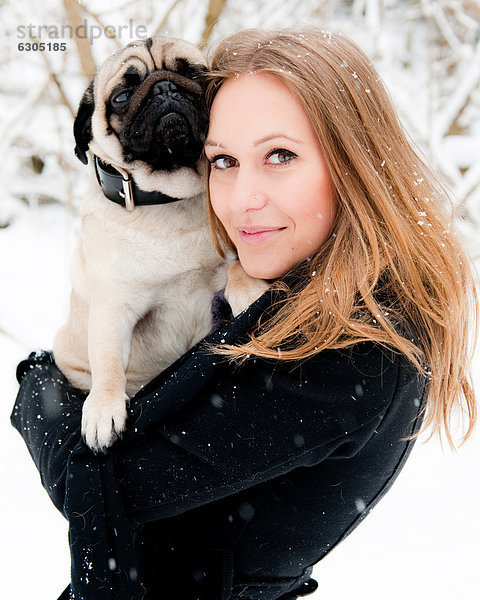 Junge Frau mit einem Mops im Schnee  Portrait