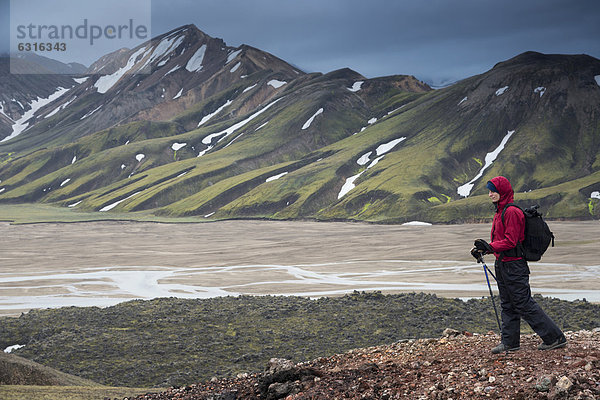 Wanderin mit Wanderstöcken  Fluss JökulgilskvÌsl  schneebedeckte Rhyolith-Berge  Landmannalaugar  Fjallabak Naturschutzgebiet  Hochland  Island  Europa