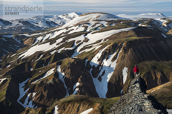 Frau bewundert Blick vom Vulkan Bl·hn_kur auf schneebedeckte Rhyolith-Berge  Landmannalaugar  Fjallabak Naturschutzgebiet  Hochland  Island  Europa