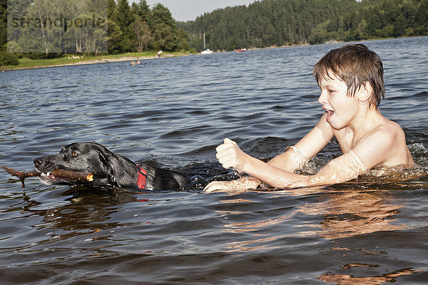 Junge spielt im See mit seinem Jagdhund