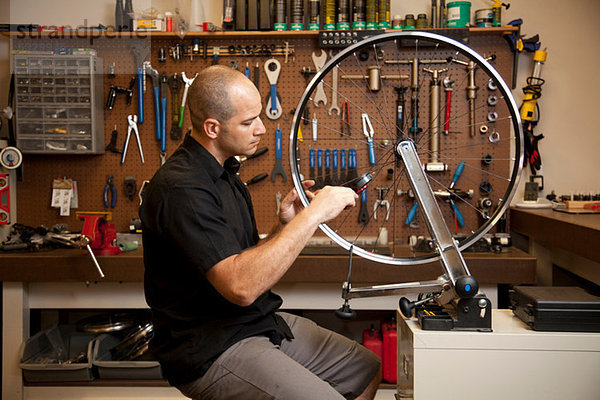 Mann befestigt Fahrradfelge in der Werkstatt