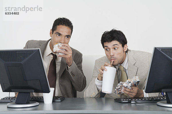 Geschäftsleute essen Fast Food am Schreibtisch im Büro