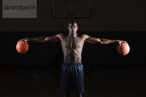 Barechested Basketballspieler hält Basketbälle in beiden Händen