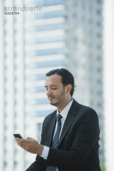 Business Executive Text Messaging mit Handy im Freien