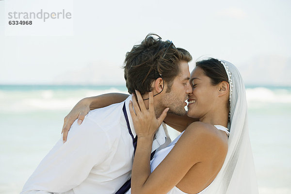 Brautpaar beim Küssen am Strand