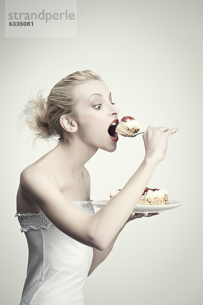 Junge Frau beim Kuchenessen  Seitenansicht  Portrait
