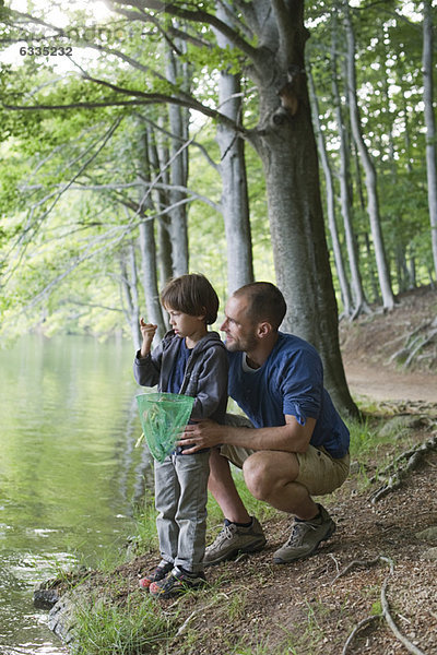 Vater und Sohn beim Fischen  Junge starrt auf kleine Fische in der Hand
