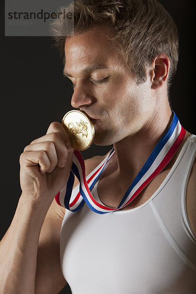 Männlicher Turner küsst Goldmedaille  Portrait