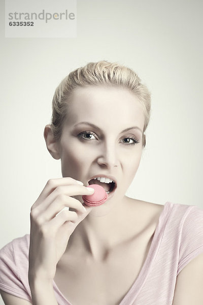Junge Frau isst Makrone  Portrait