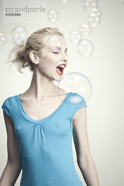 Junge Frau umgeben von Blasen mit geöffnetem Mund