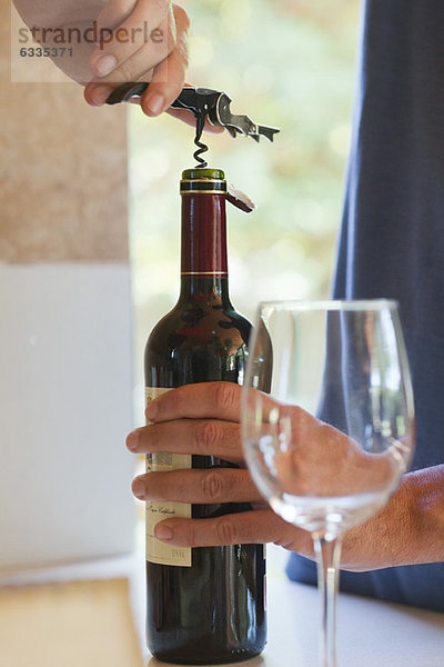 Mann entkorkt Flasche Wein  beschnitten