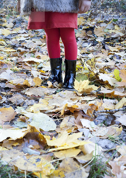 Mädchen auf Herbstblättern stehend  niedriger Schnitt