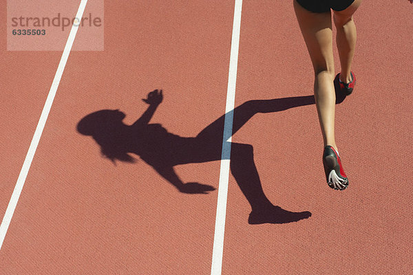 Sportlerin  die auf der Bahn läuft  niedriger Abschnitt  Fokus auf Schatten